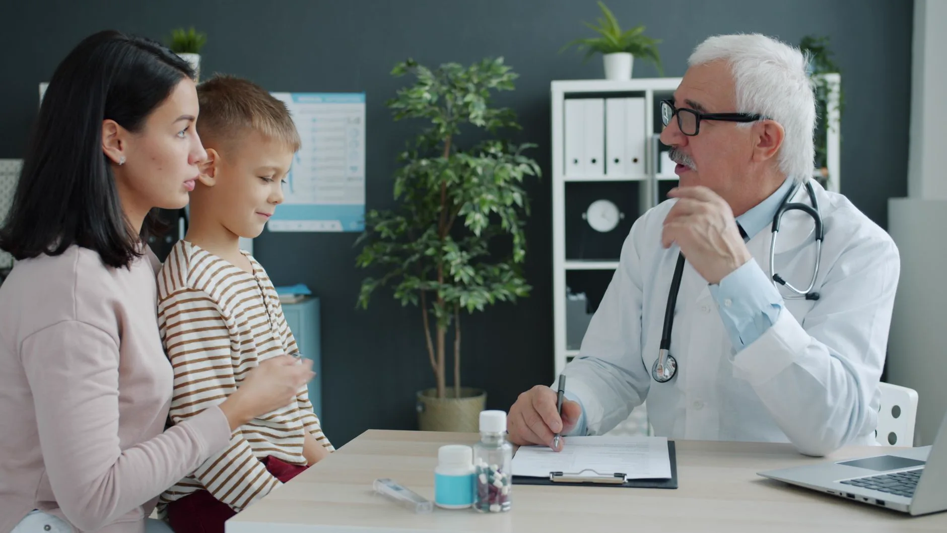 Médico conversa com mãe e criança em consultório